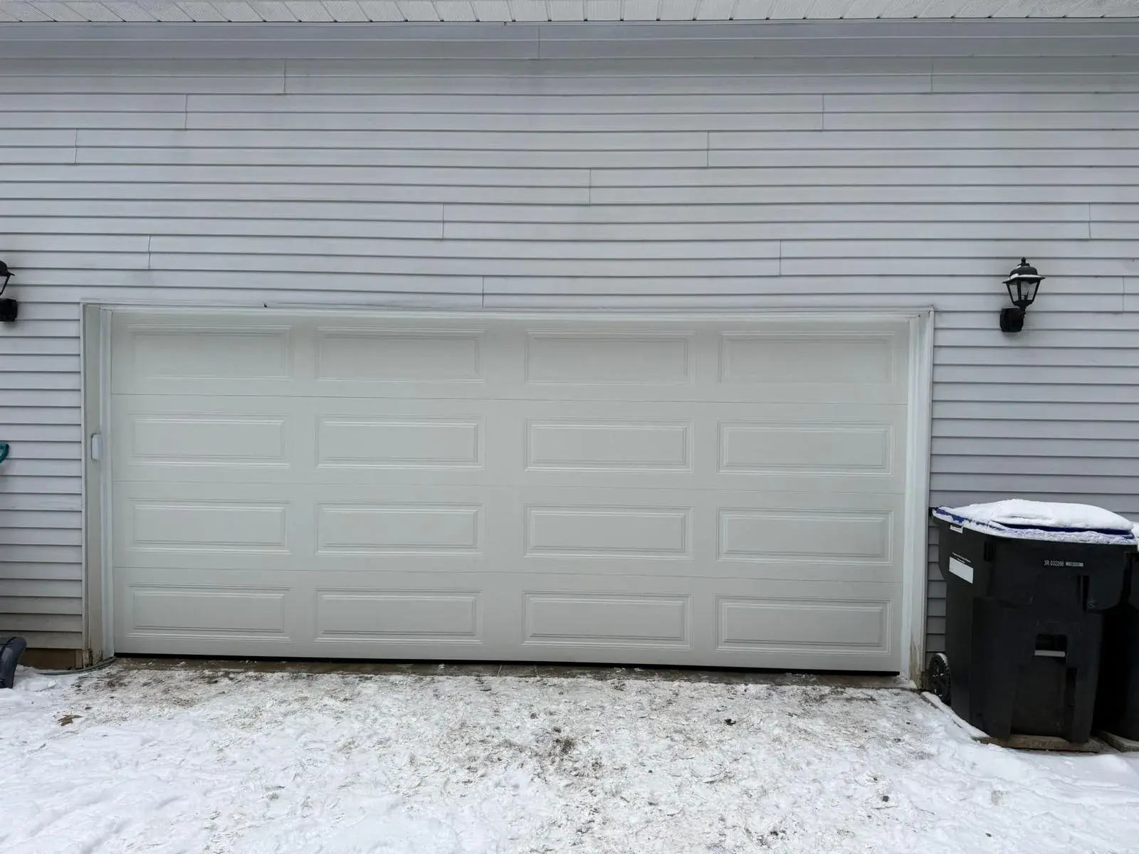 White garage door installed on a home with snow on the driveway