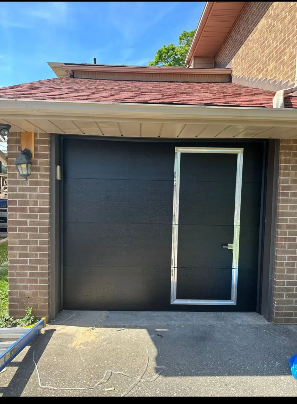 Black garage door with pedestrian entry panel during installation
