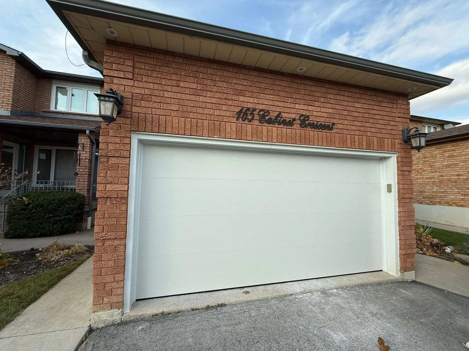 White flat-panel garage door installed on a brick home
