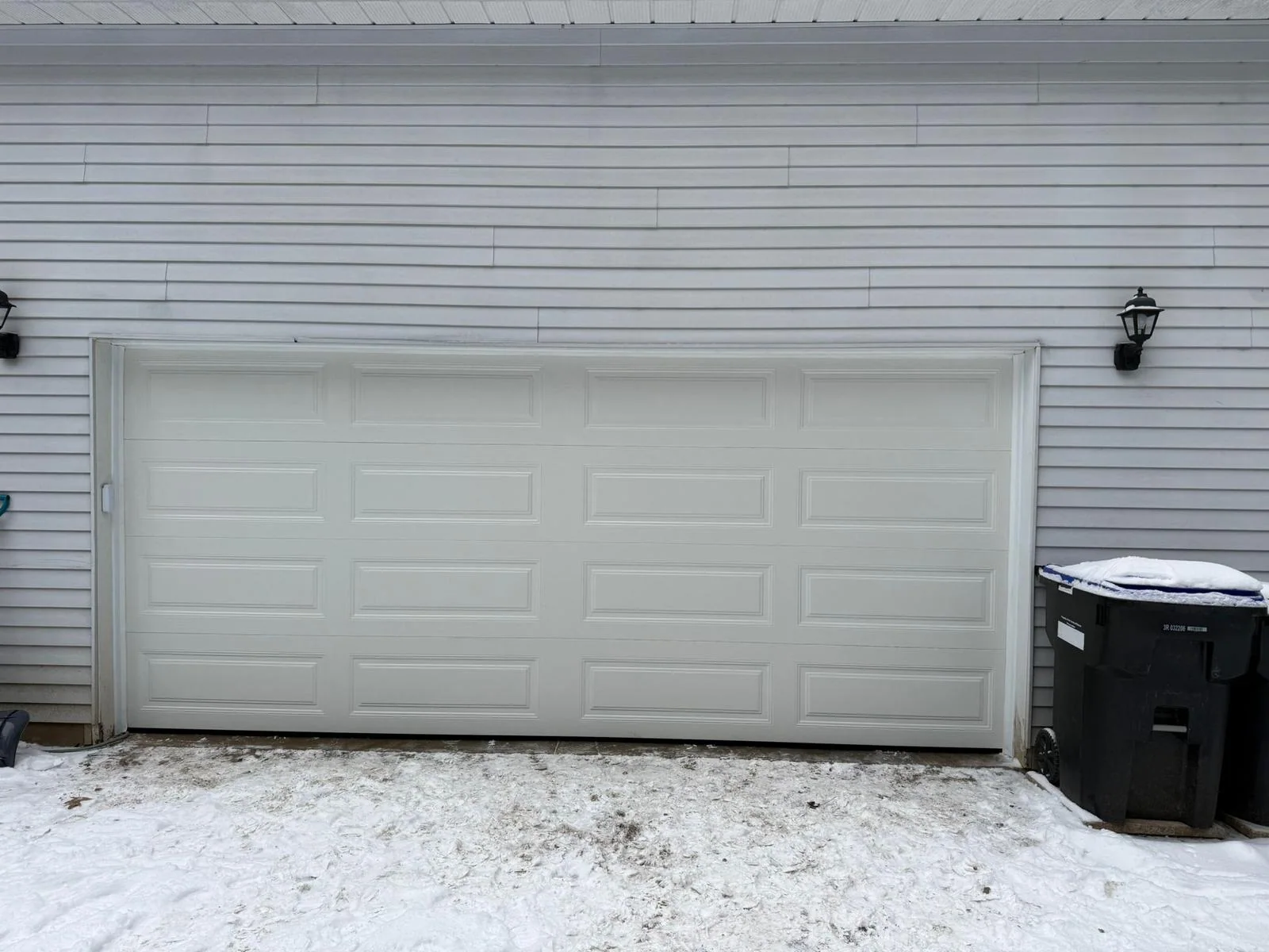 White garage door installed on a home with snow on the driveway